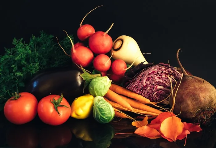 Assortment of fresh colourful vegetables and fruits including tomatoes, peppers, leafy greens, and citrus