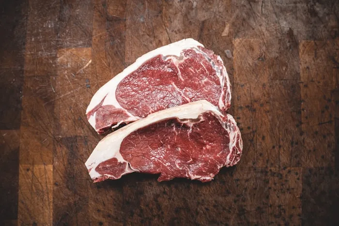 Assortment of premium fresh meat cuts including beef steaks and lamb chops displayed on a wooden cutting board
